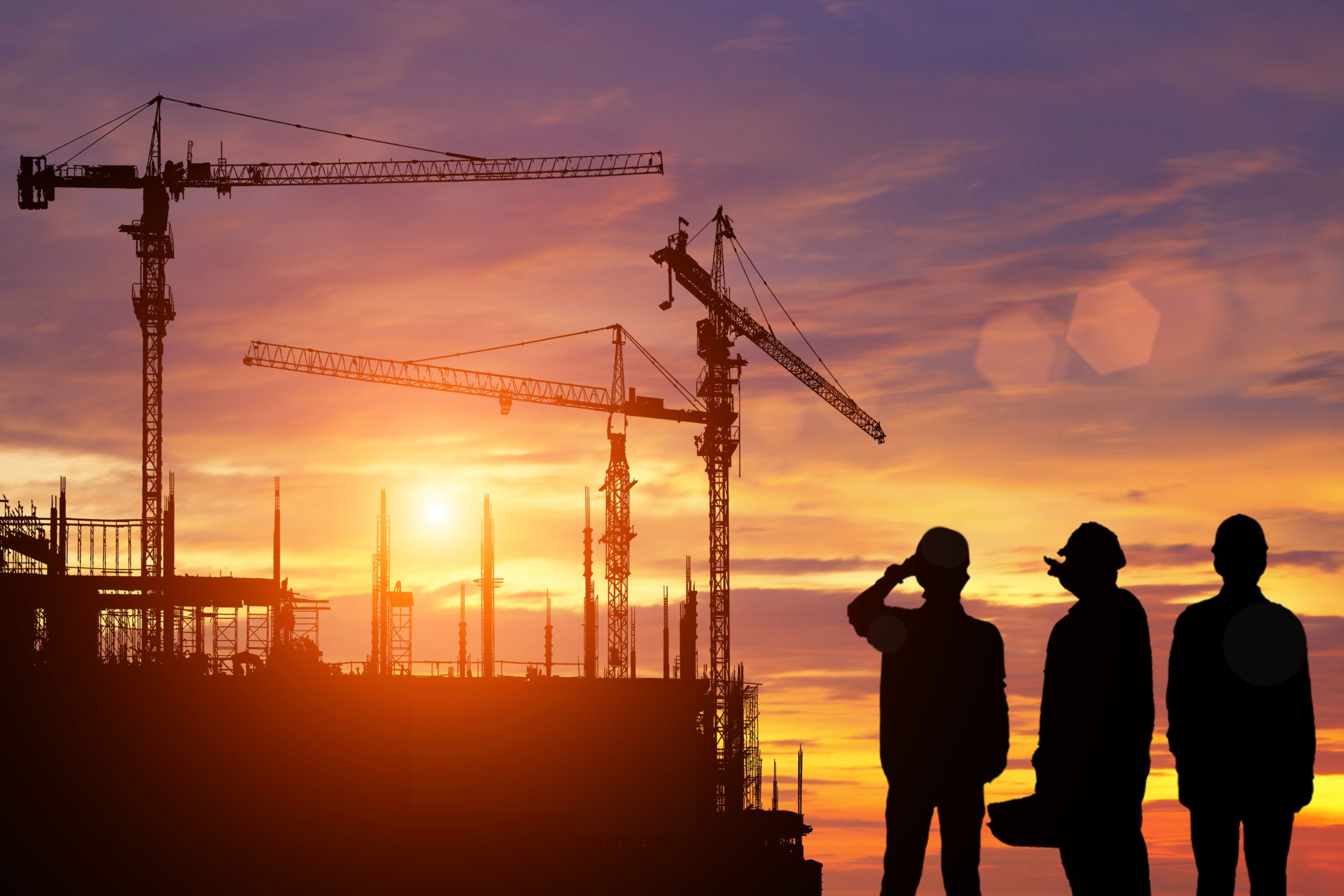 Engineers,Work,In,Front,Of,The,Construction,Site,At,Sunset.
